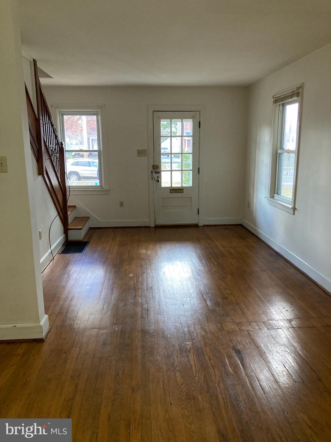 an empty room with wooden floor and windows