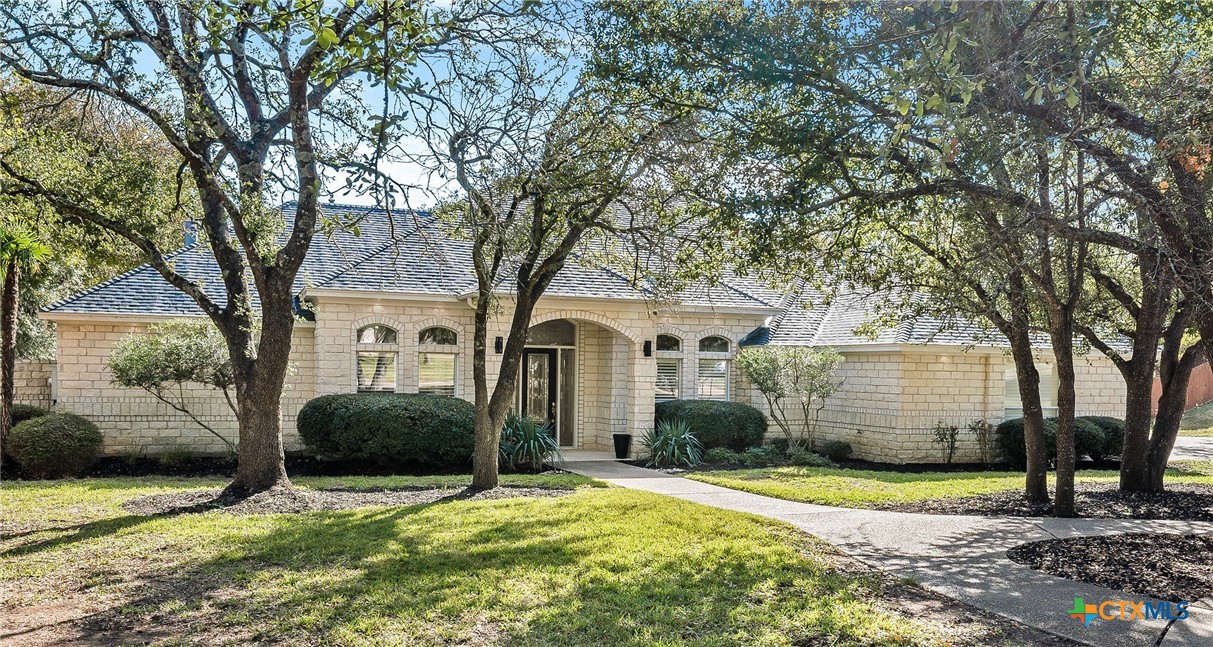 a front view of a house with a garden and tree