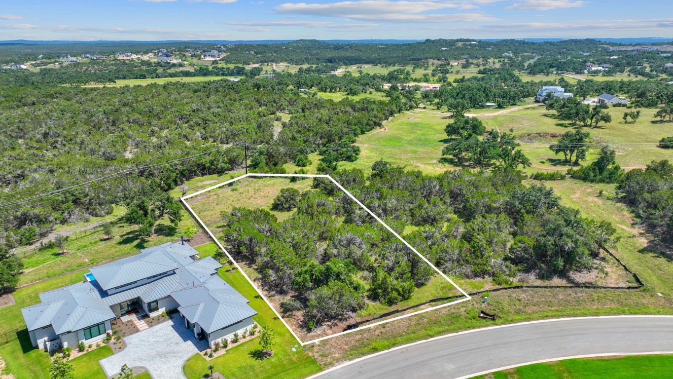 an aerial view of a residential houses with outdoor space and trees