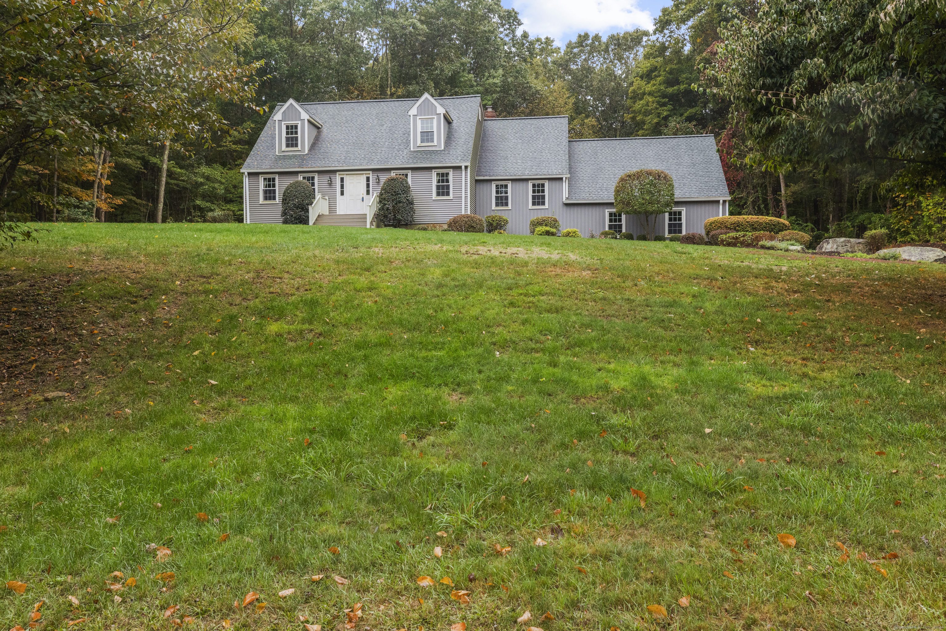 a view of a house with a big yard and large trees