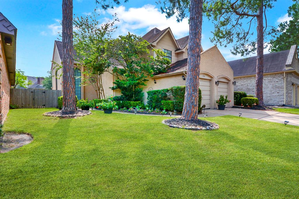 a front view of a house with garden and tree