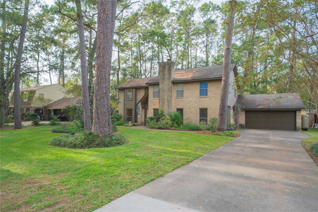 a view of a house with a yard and a large tree