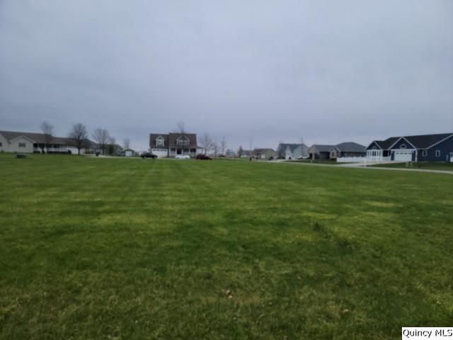 a view of a green field with lawn chairs and wooden fence