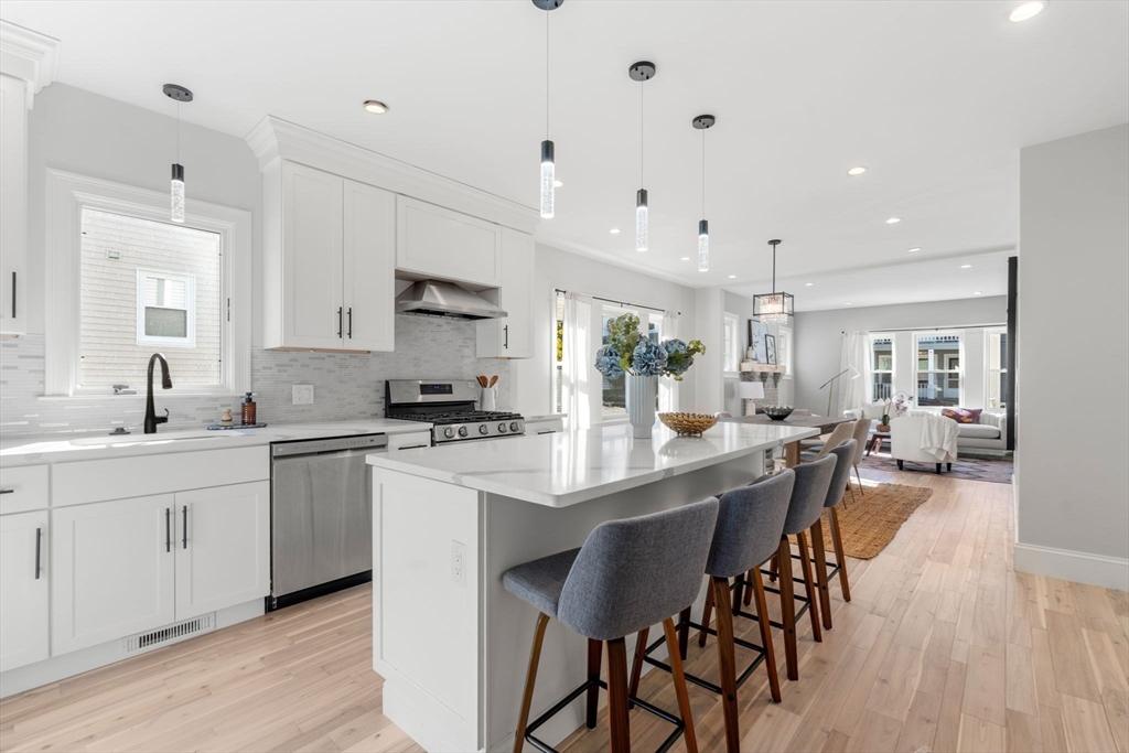 a large kitchen with kitchen island a dining table chairs and white cabinets