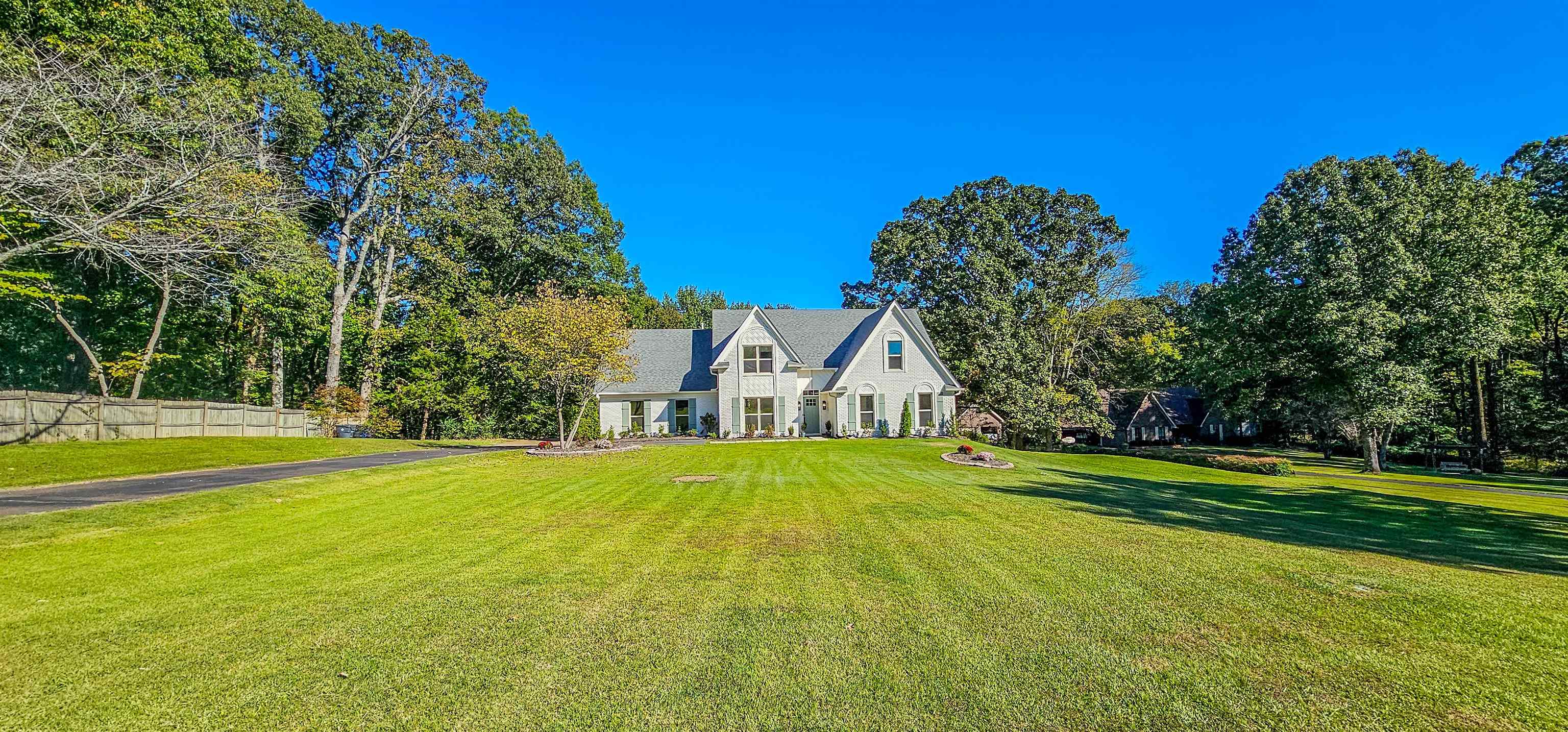 a view of big house with a big yard and large trees