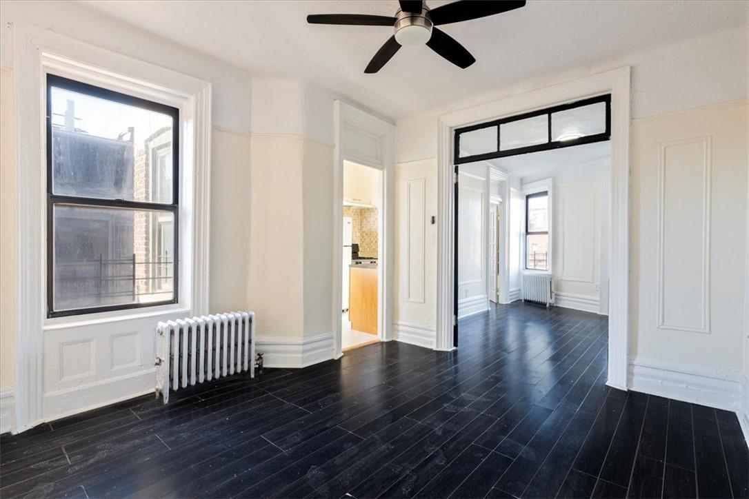 Spare room with radiator, dark wood-type flooring, and plenty of natural light