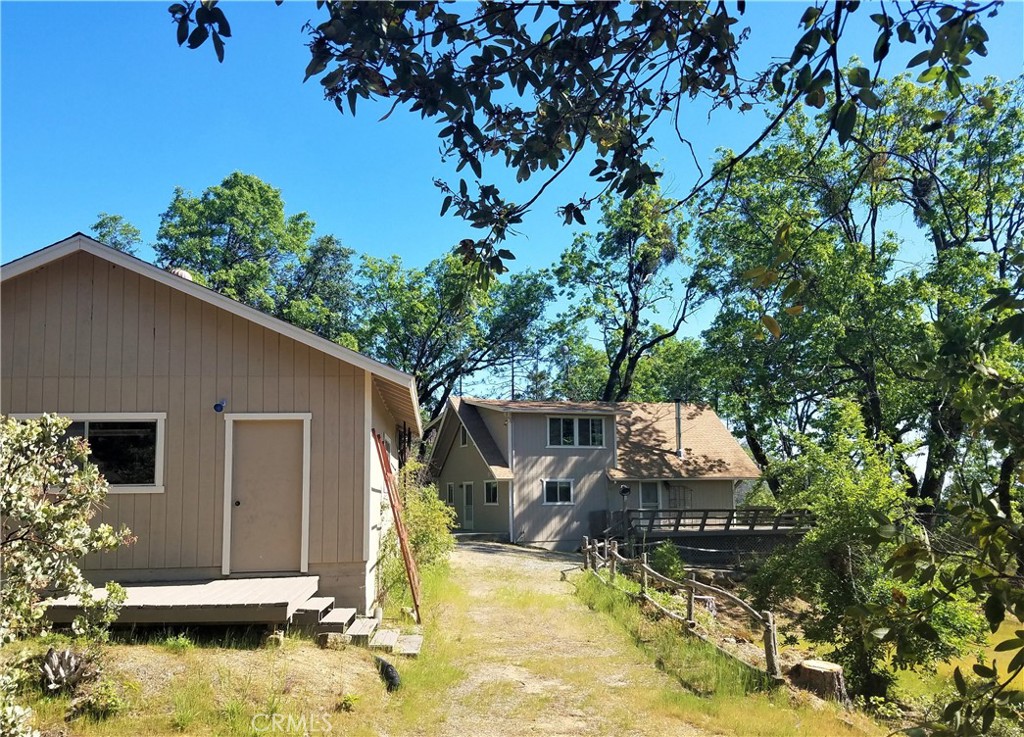 a view of house with yard outdoor seating and covered with tall trees