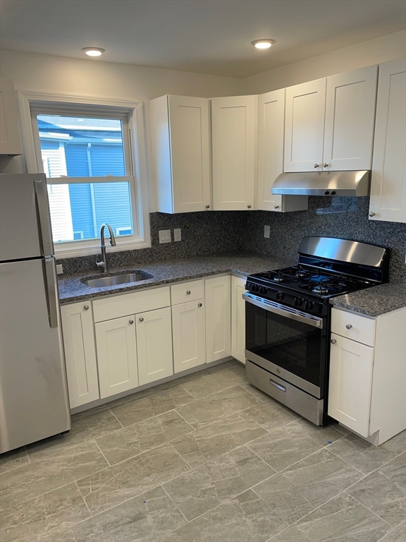 a kitchen with granite countertop white cabinets and stainless steel appliances