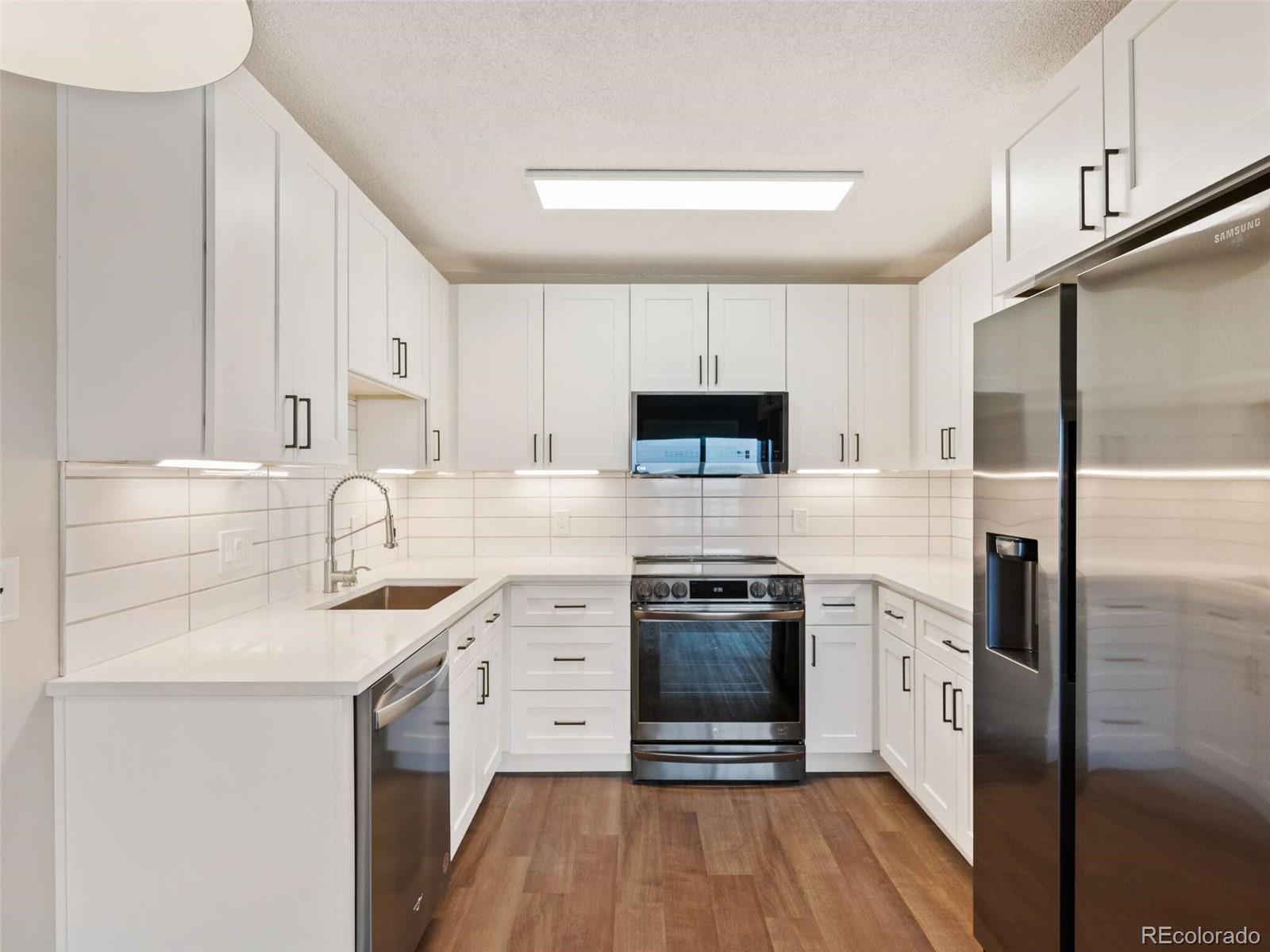 a kitchen with a sink cabinets stainless steel appliances and a counter top space