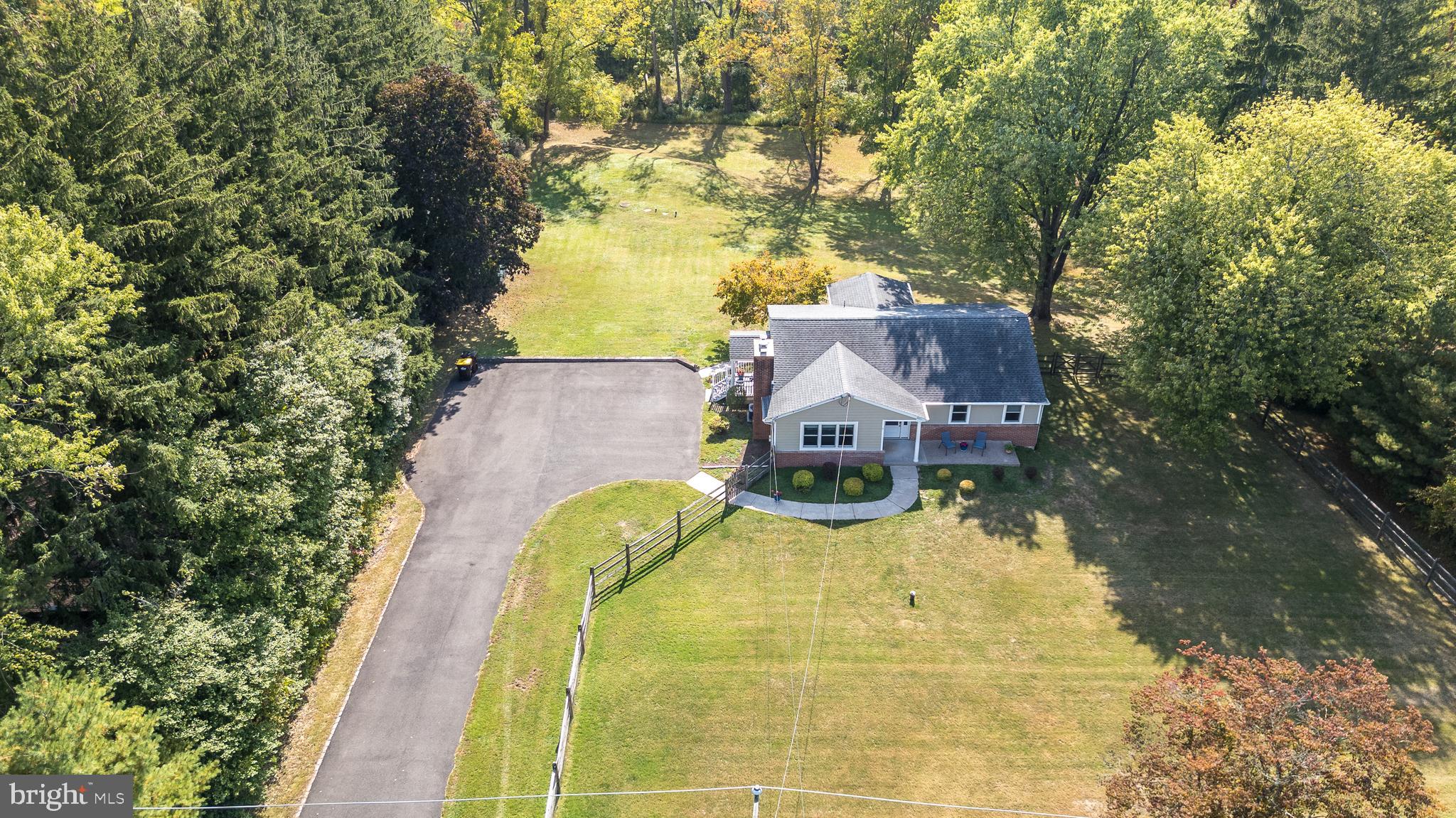 an aerial view of a house with swimming pool and large trees