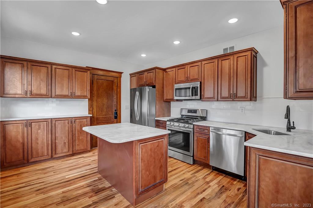 a kitchen with stainless steel appliances granite countertop wooden cabinets a stove a sink and dishwasher with wooden floor