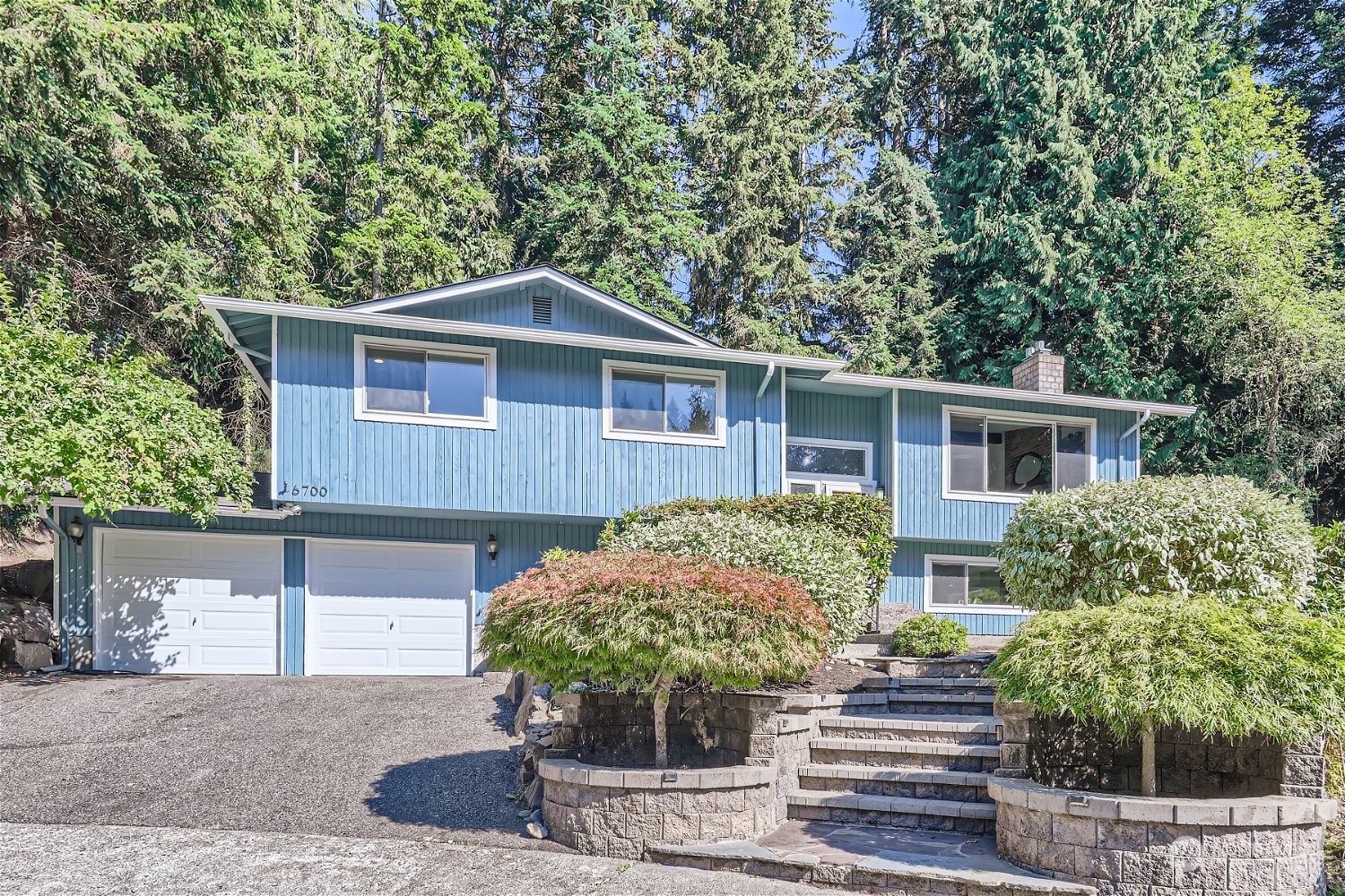 a front view of house with yard and trees in the background