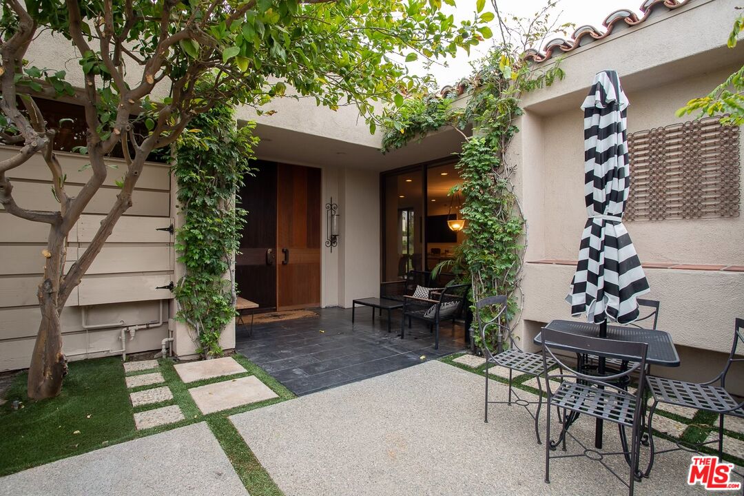 a patio with table and chairs and potted plants