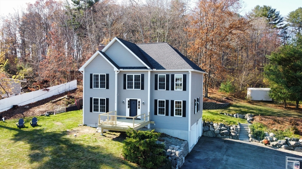 a white house with a large pool and lawn chairs next to a yard