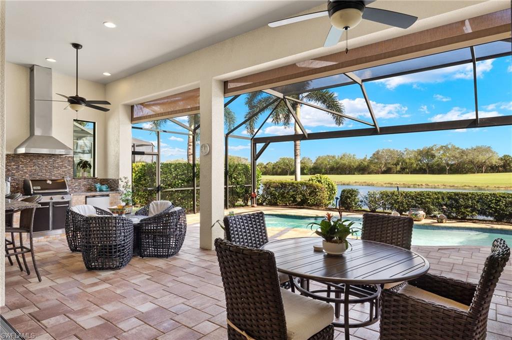 View of patio with an outdoor kitchen, glass enclosure, ceiling fan, and a grill