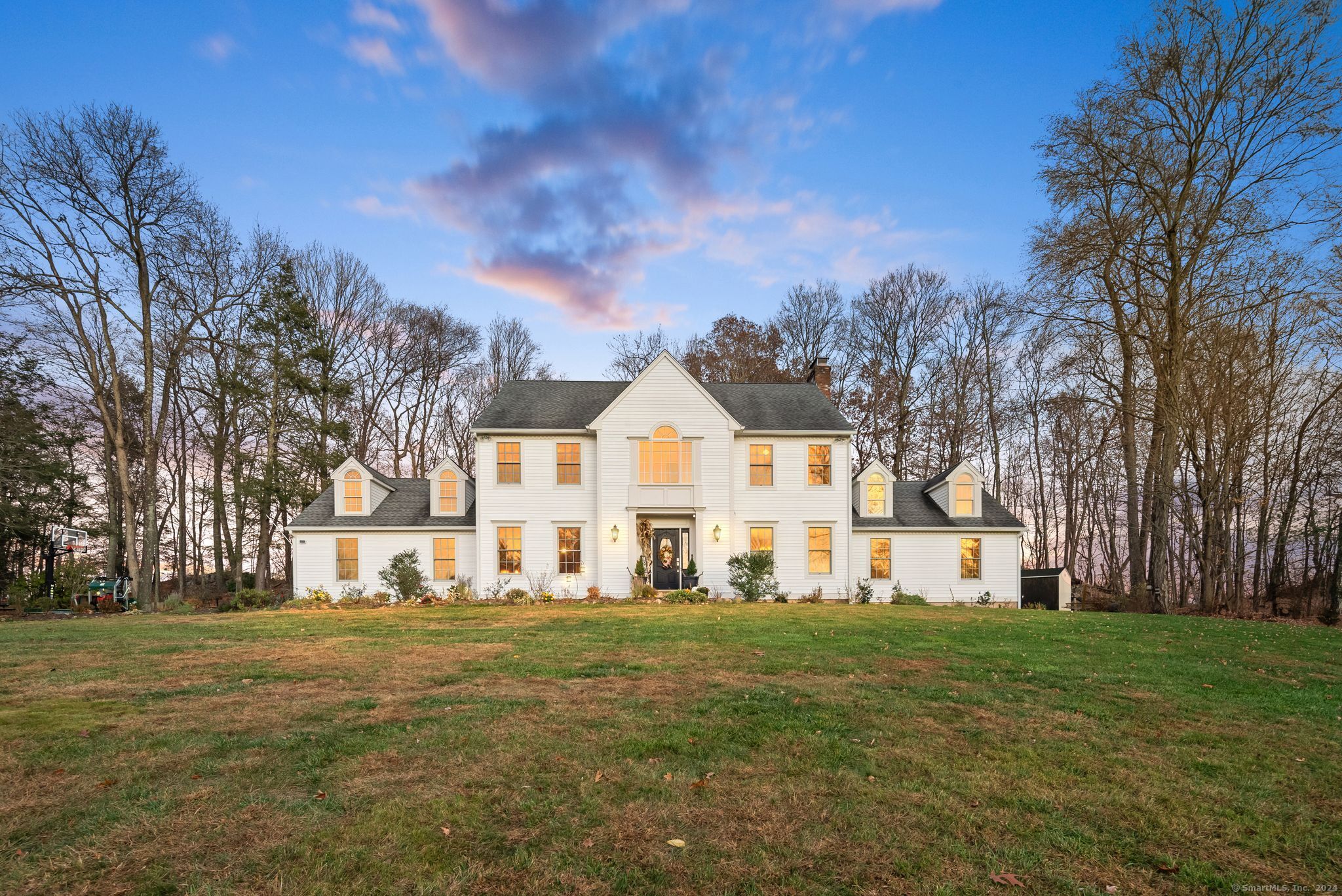 a view of a white house with a big yard and large trees