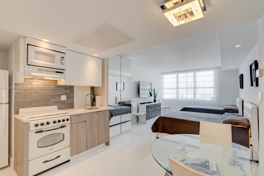 a large white kitchen with stainless steel appliances a stove a sink a refrigerator and cabinets