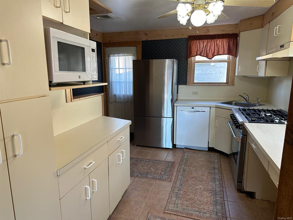 Tiled Kitchen featuring ceiling fan, sink, stainless steel appliances, and a wealth of natural light