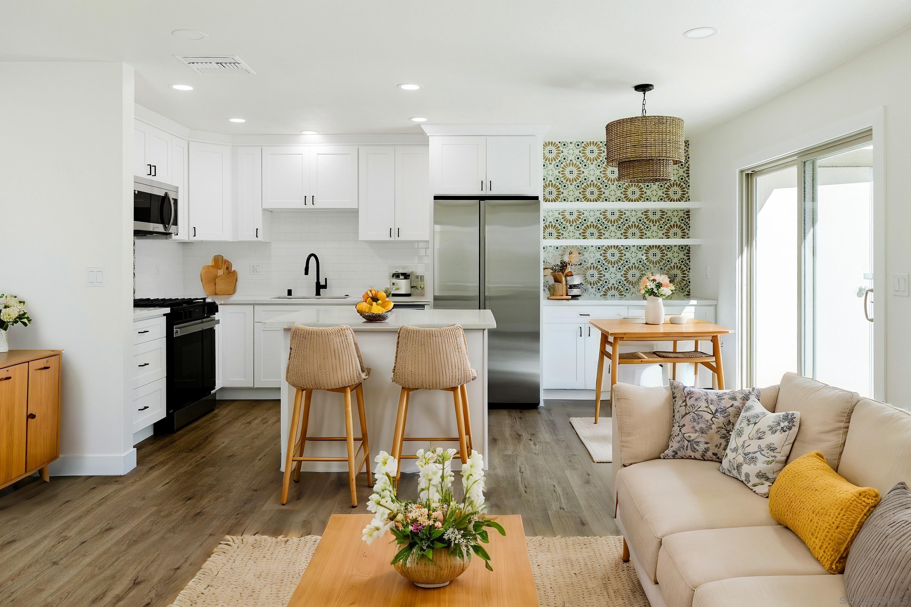 a living room with stainless steel appliances furniture a refrigerator and a kitchen