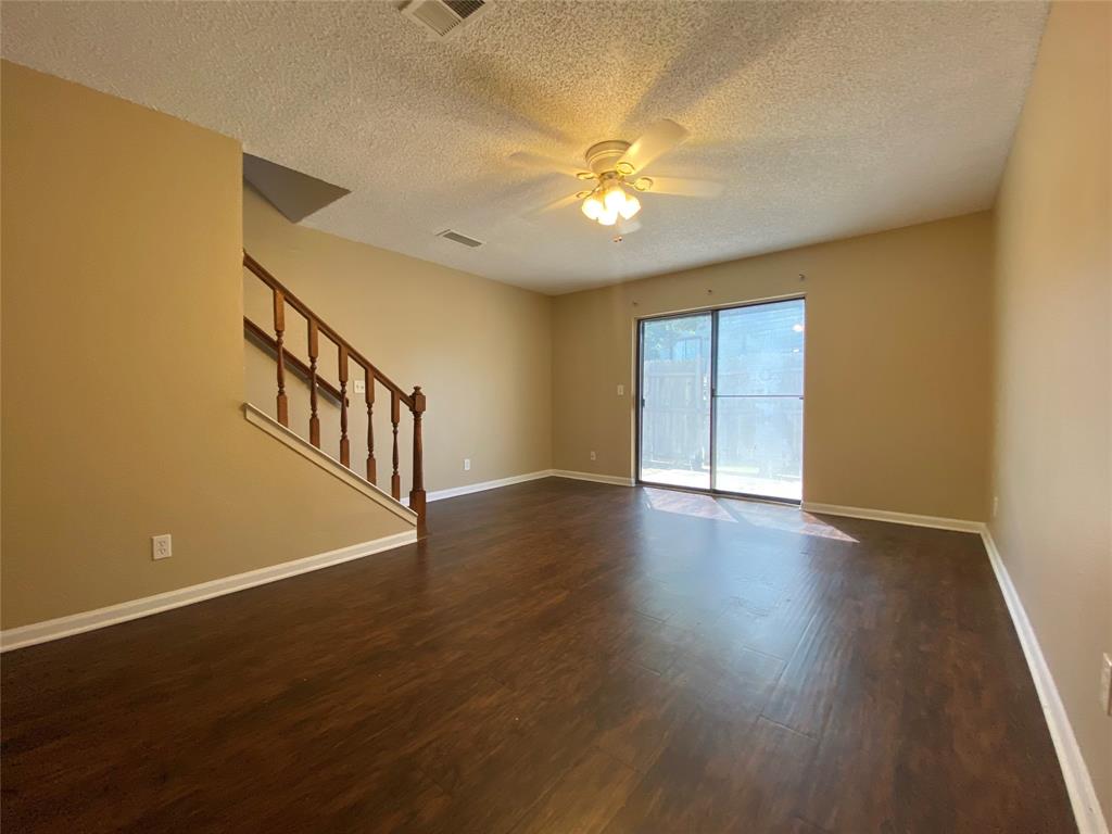 a view of an empty room with wooden floor and a chandelier fan