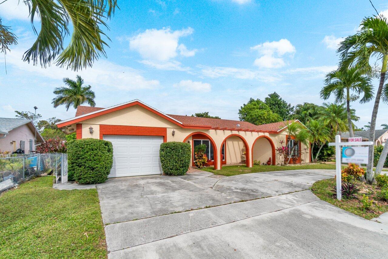 a view of a house with a yard and palm trees