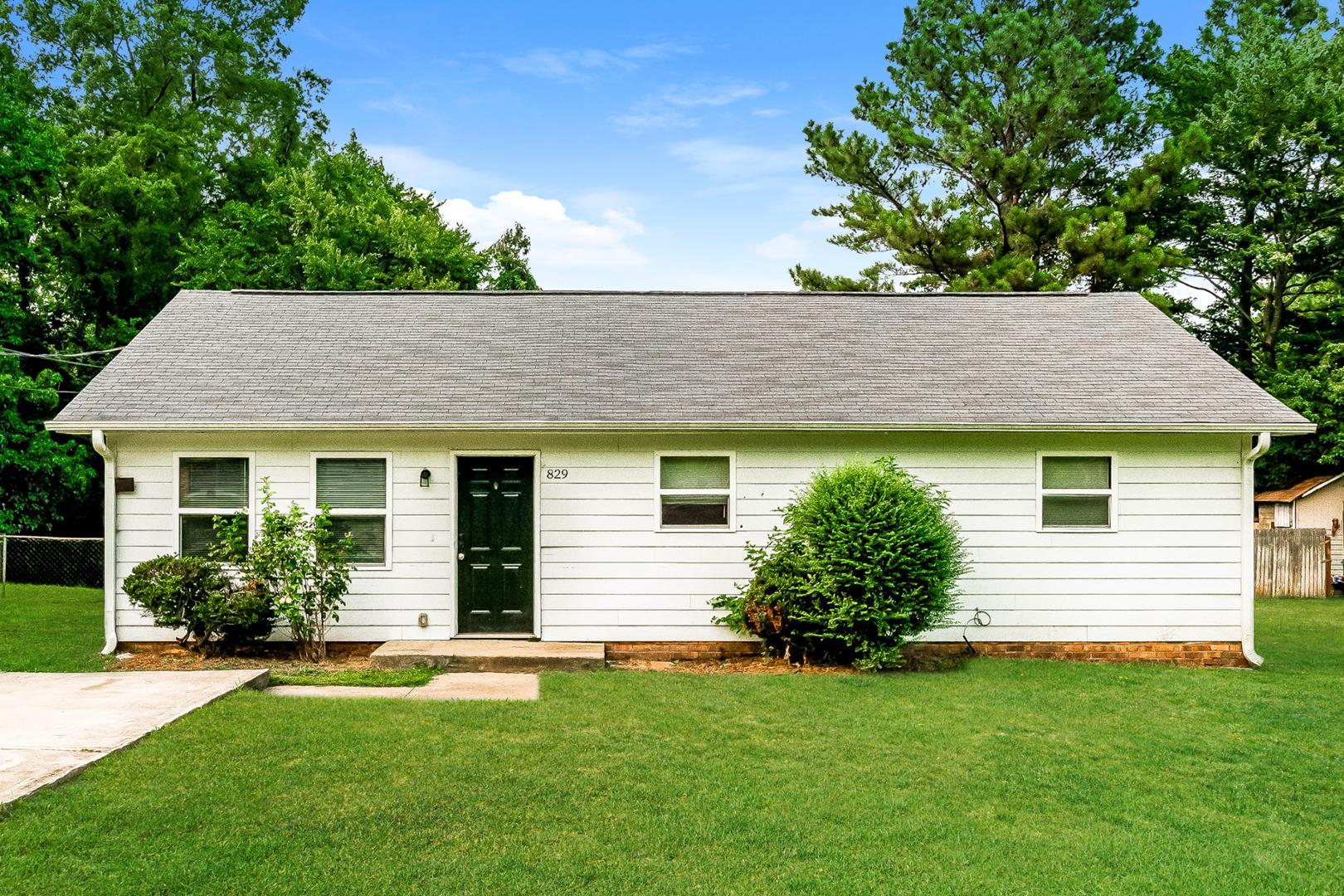 a view of a house with a yard potted plants and a large tree