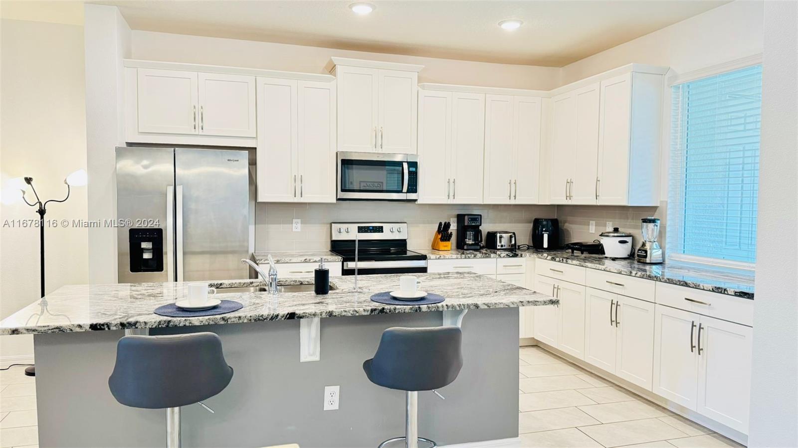 a kitchen with stainless steel appliances granite countertop a sink a stove a refrigerator cabinets and chairs