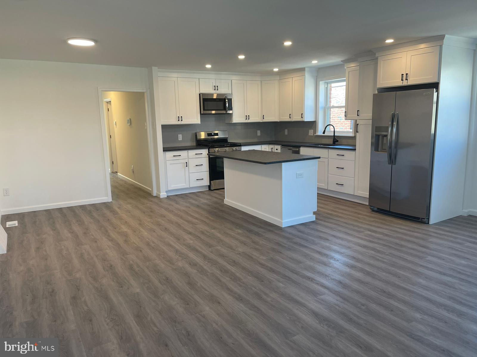 a kitchen with stainless steel appliances wooden floors and white cabinets