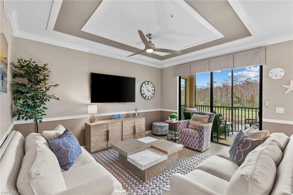 Living room with ceiling fan, crown molding, and a tray ceiling