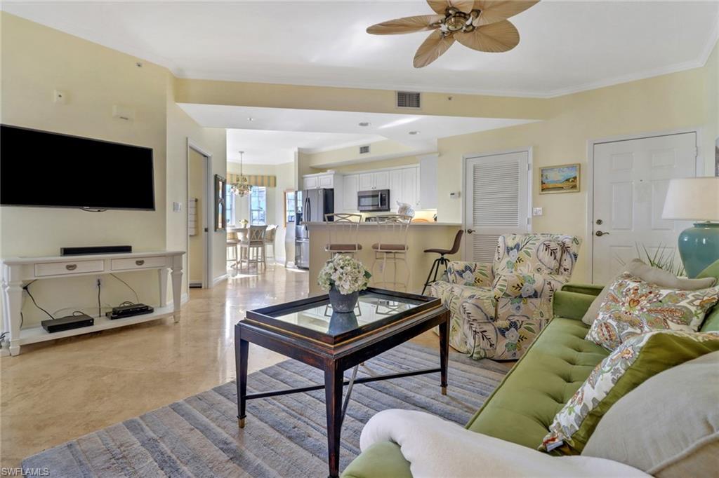 Living room featuring ceiling fan with notable chandelier and crown molding