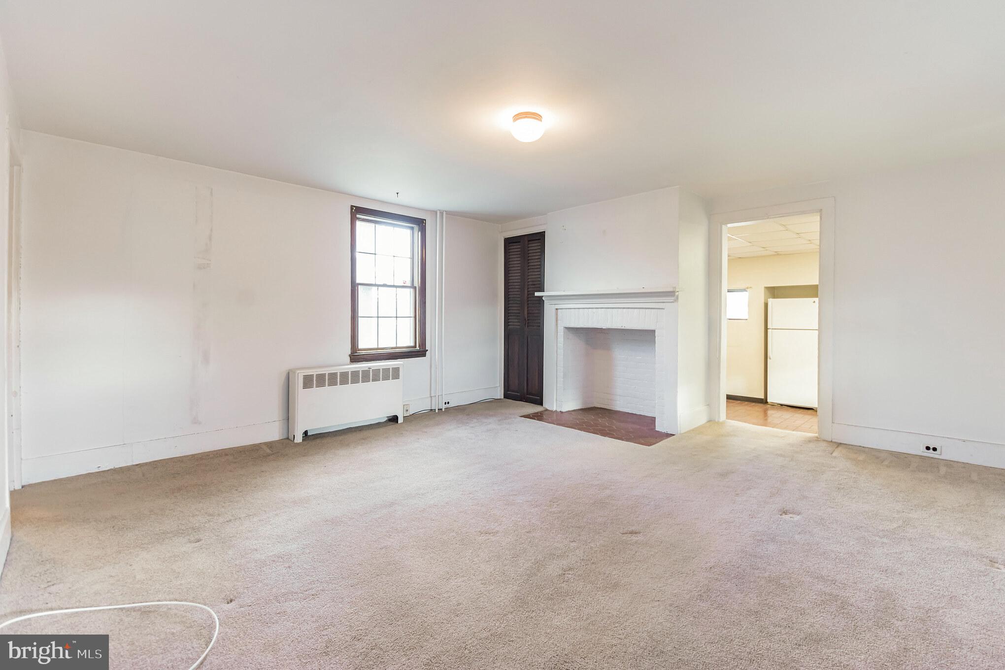 an empty room with windows and fireplace