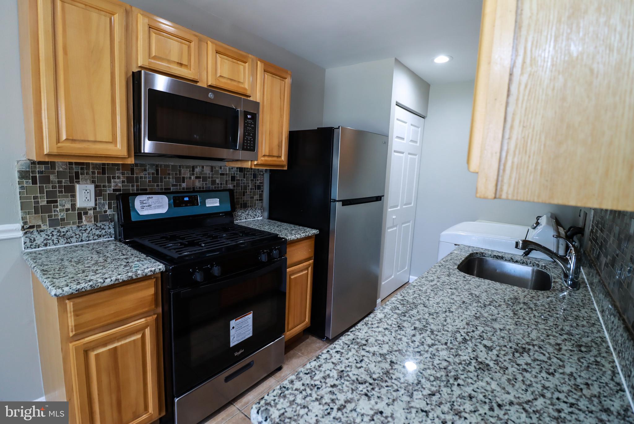 a kitchen with granite countertop a sink stove and refrigerator