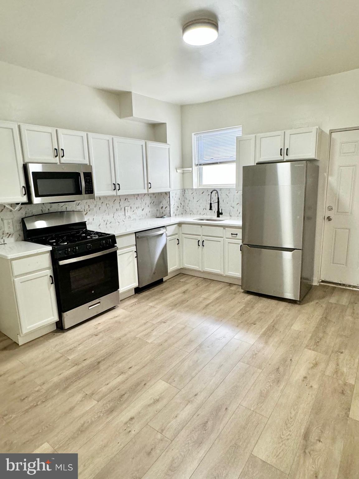 a kitchen with granite countertop a refrigerator stove top oven and sink