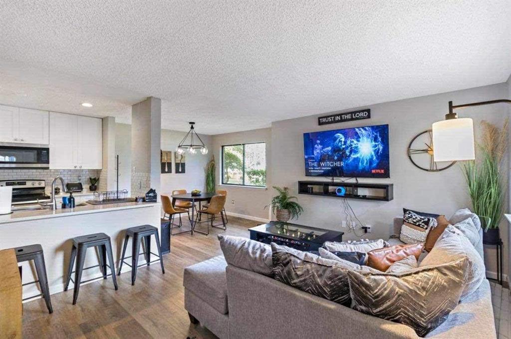 a living room with furniture kitchen view and a wooden floor