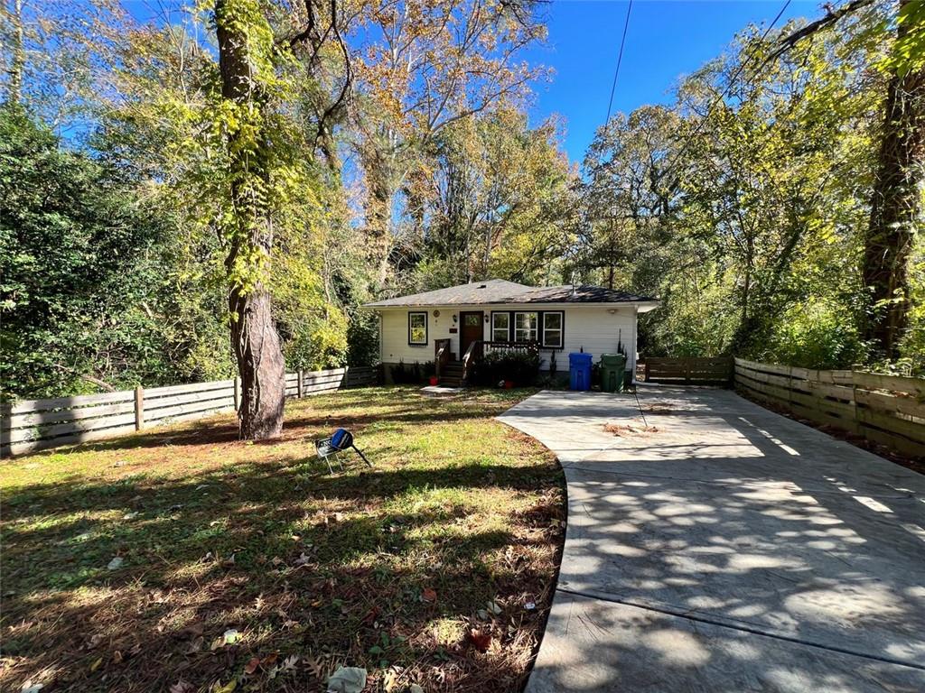 a view of house with yard outdoor seating and covered with trees