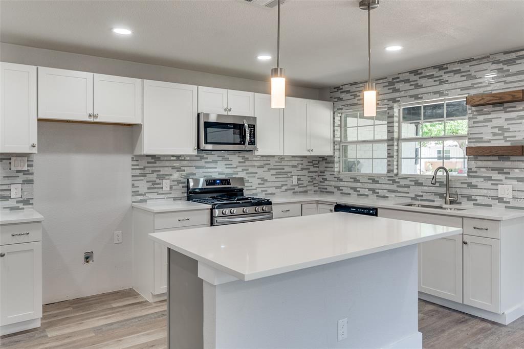 a kitchen with a sink a stove a microwave and cabinets