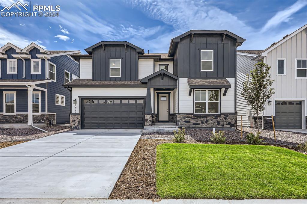 View of front facade featuring a front yard and a garage