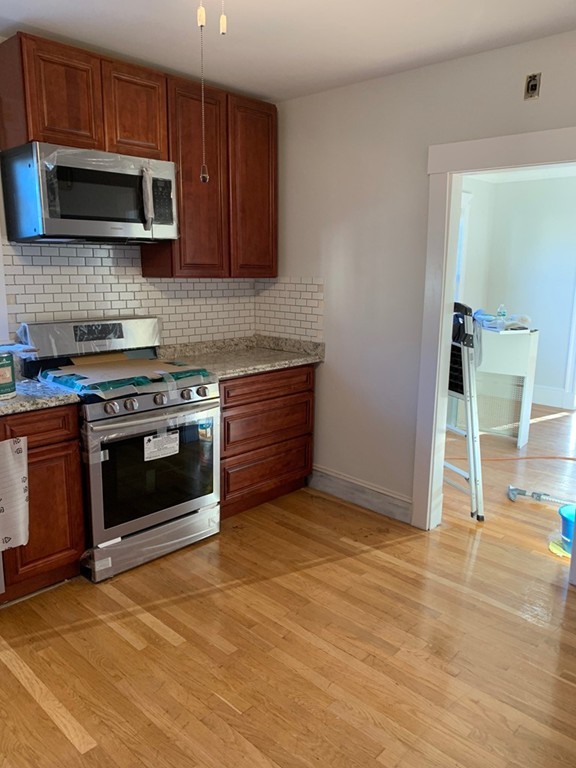 a kitchen with granite countertop a stove top oven microwave and cabinets