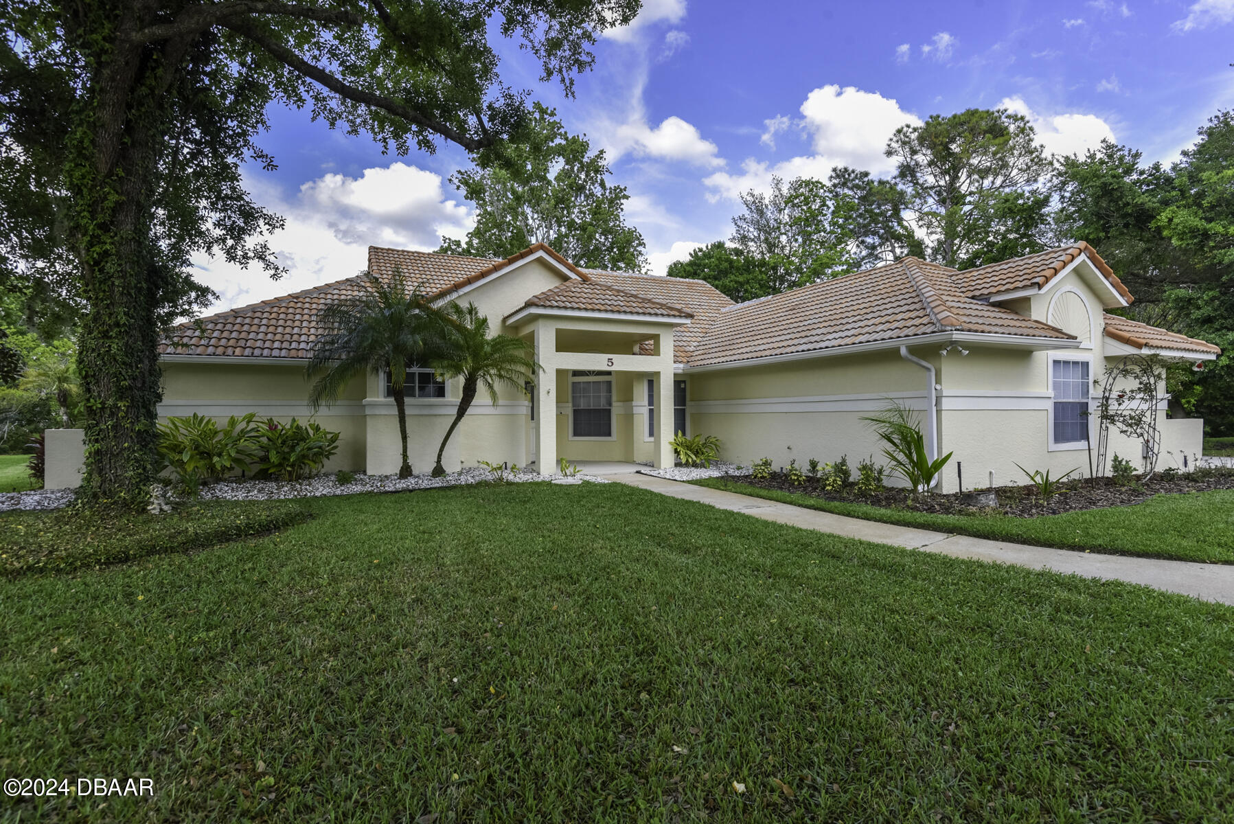 a front view of a house with a garden and plants