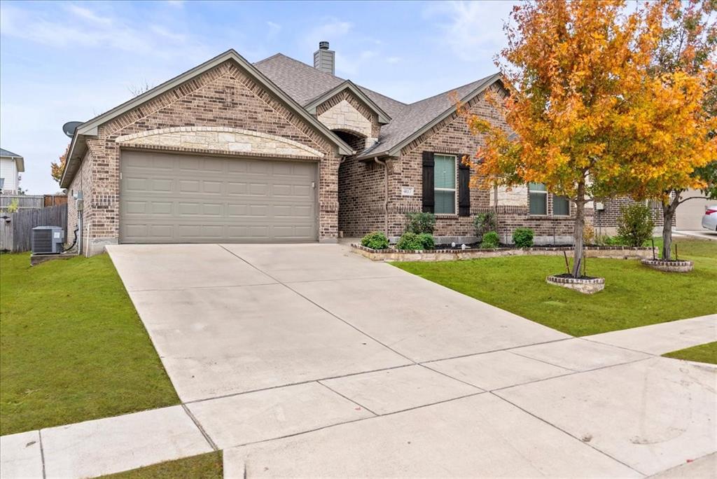 View of front of house with central AC unit, a garage, and a front yard