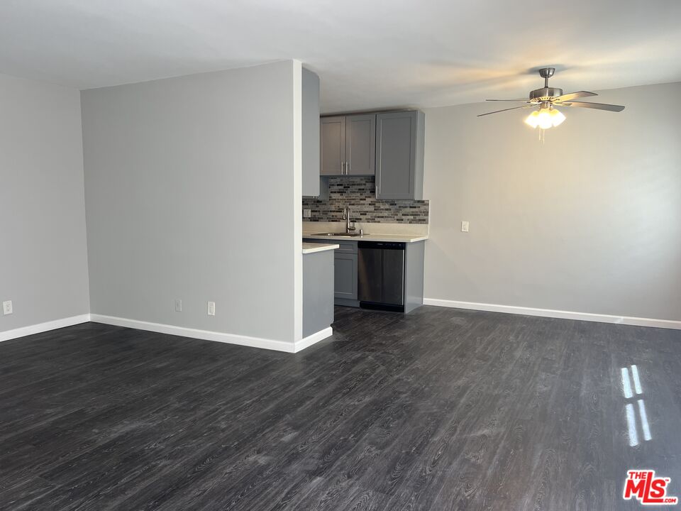 a view of kitchen and empty room with wooden floor