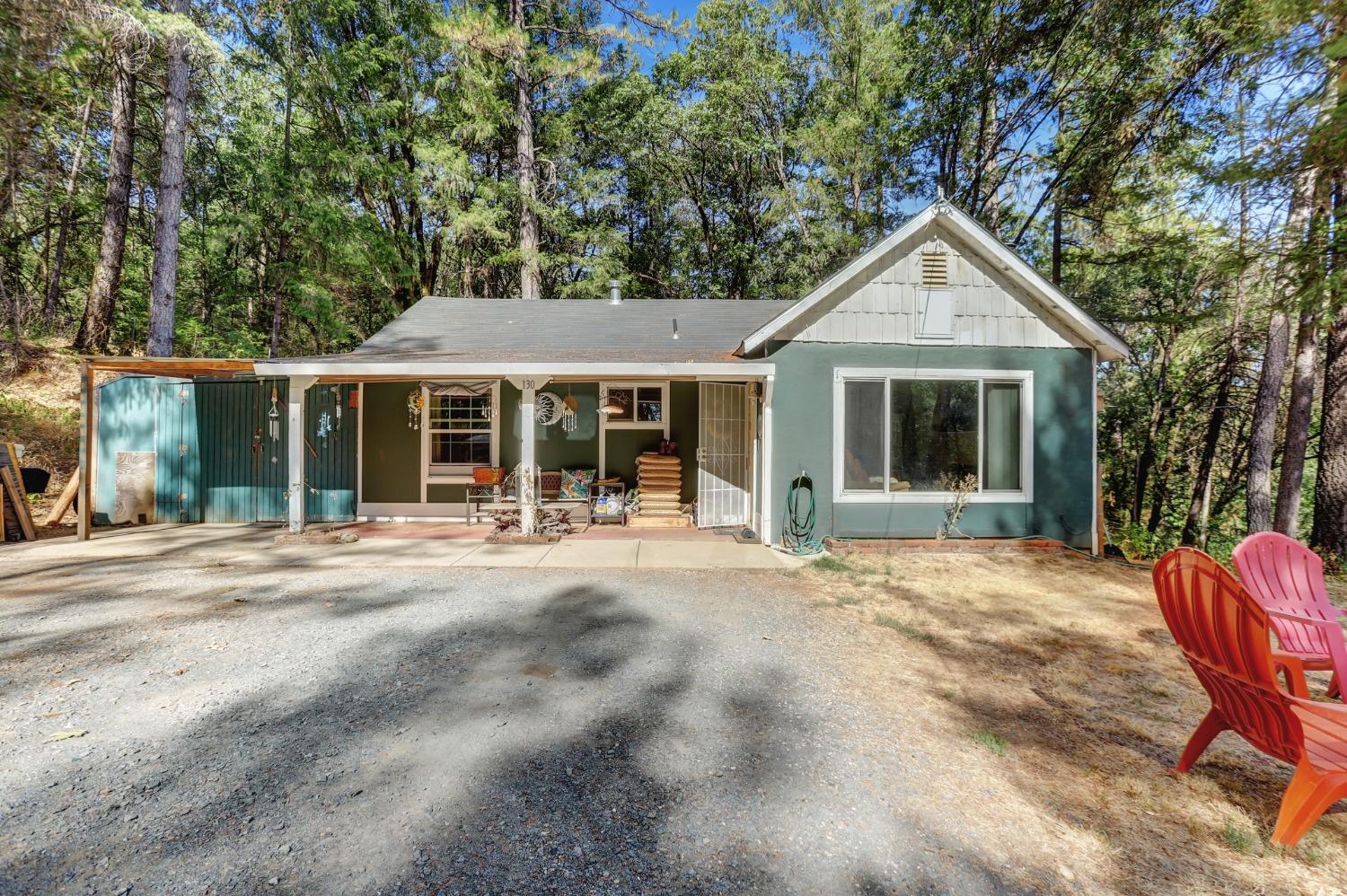 a front view of a house with a yard chairs and floor to ceiling window