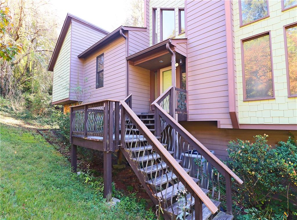 a view of a house with a small yard and wooden deck