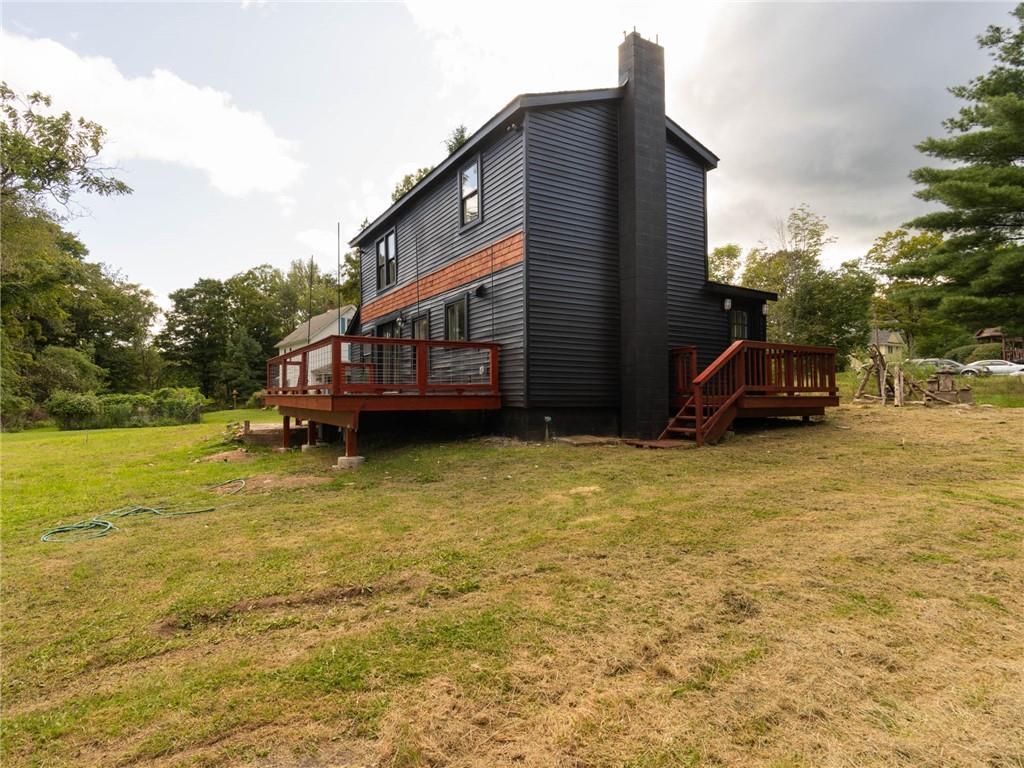 Rear view of house featuring a deck and a lawn