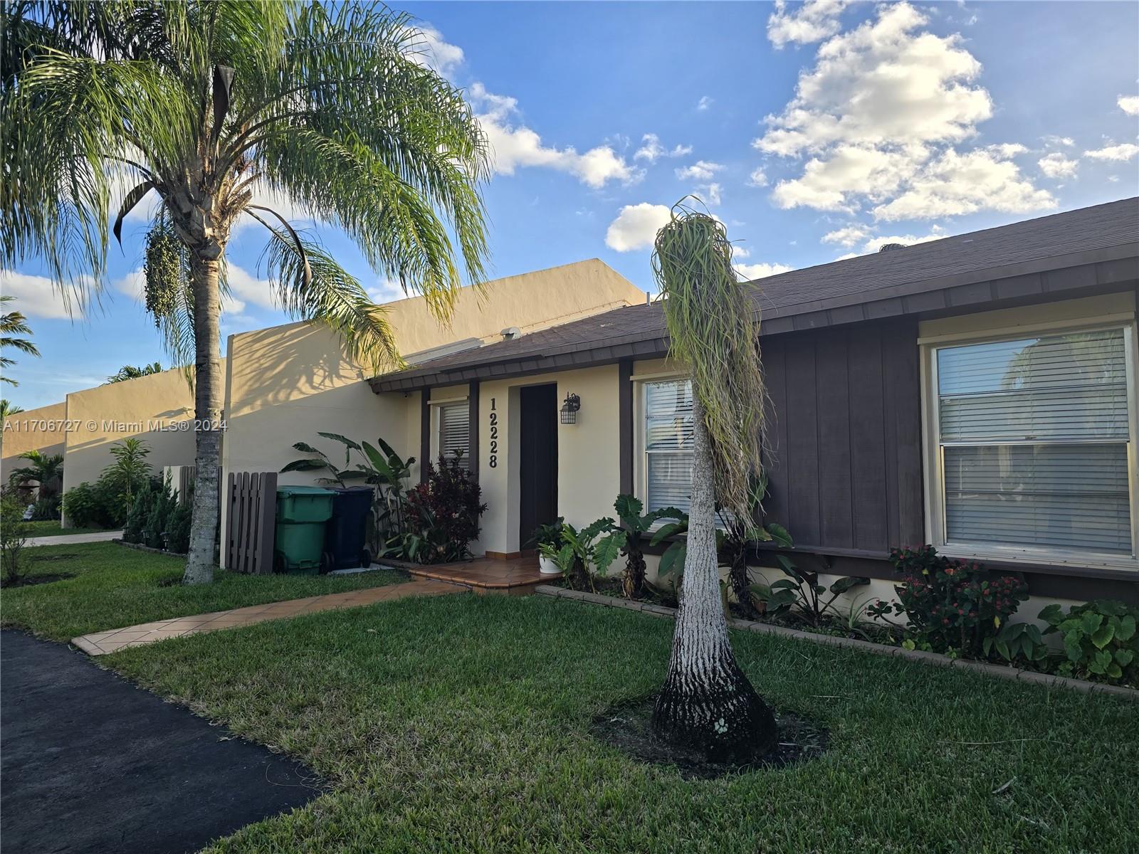 a view of a house with a yard and palm trees