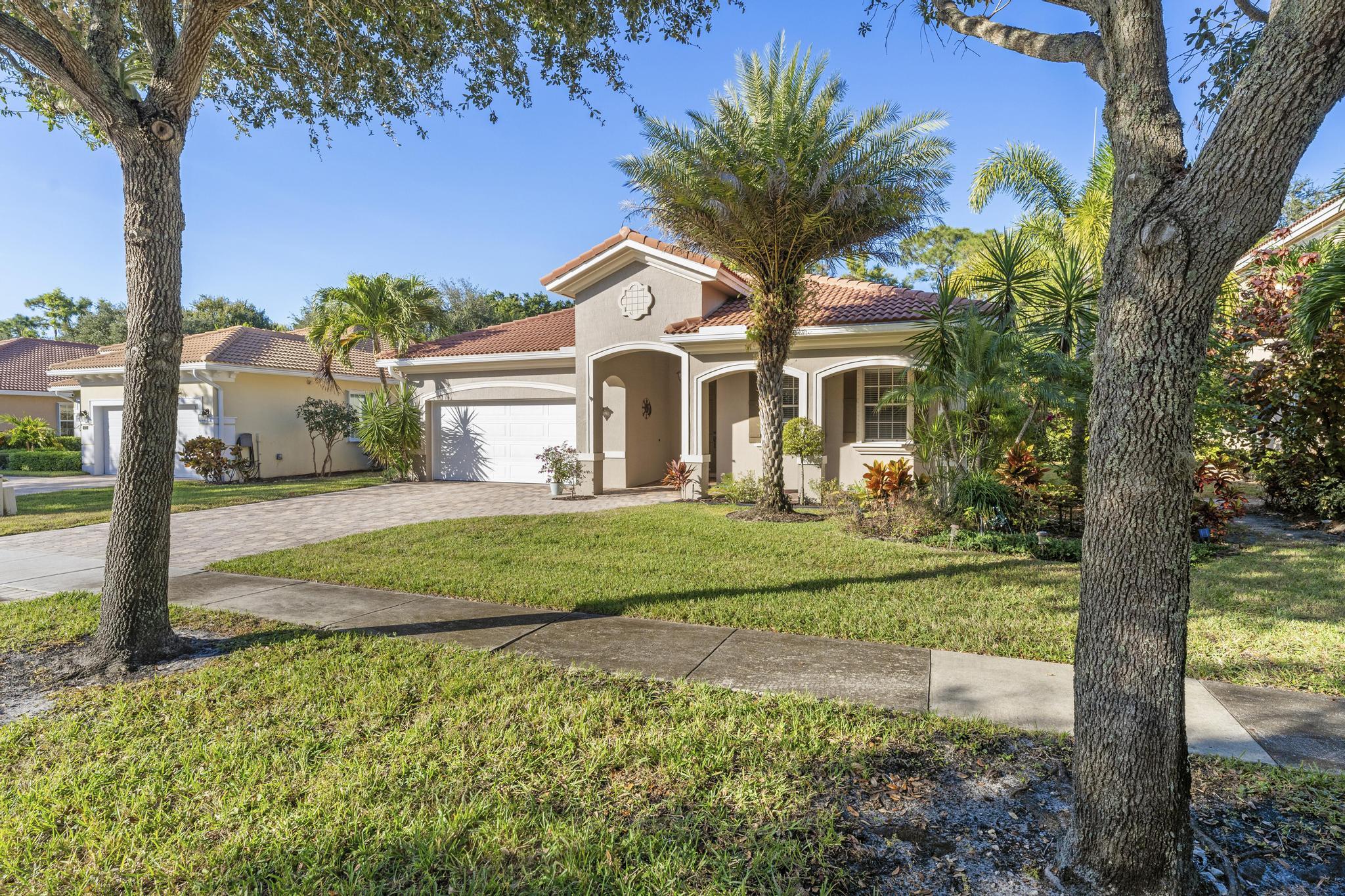 a front view of a house with a yard and palm trees