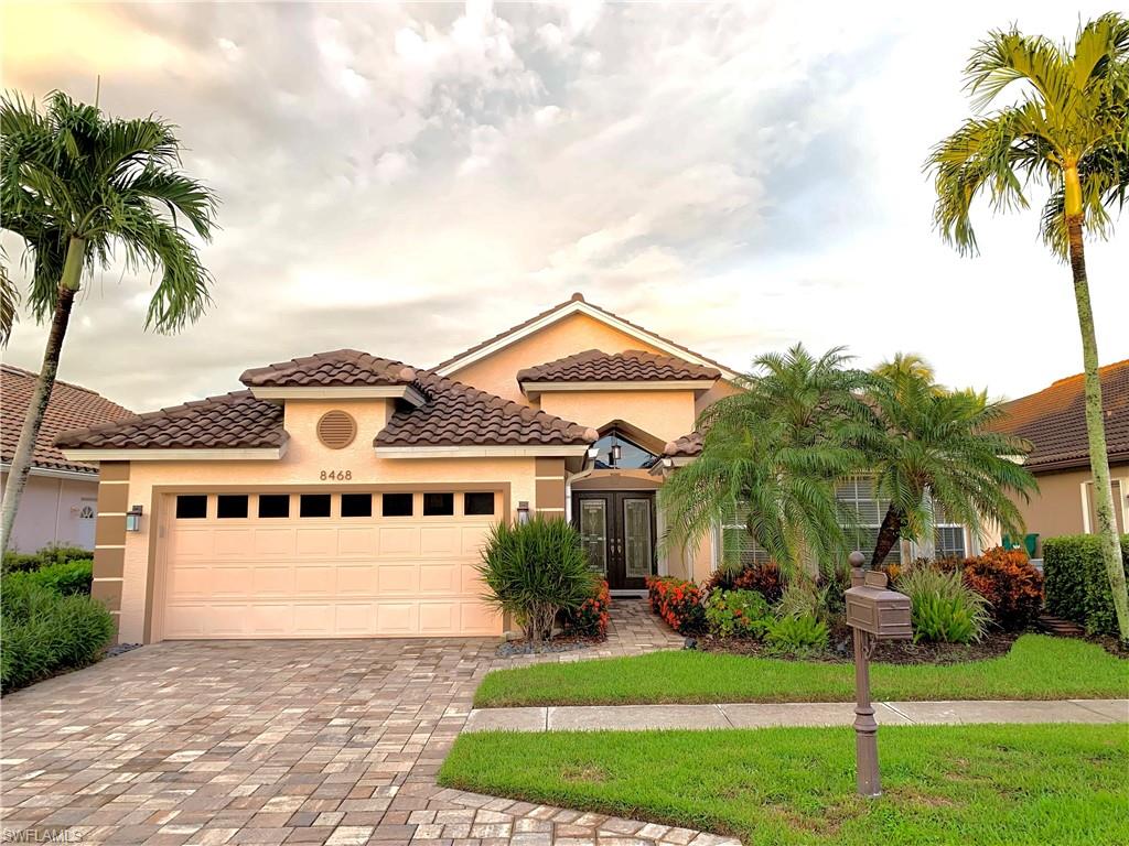 a view of a white house next to a yard with palm trees