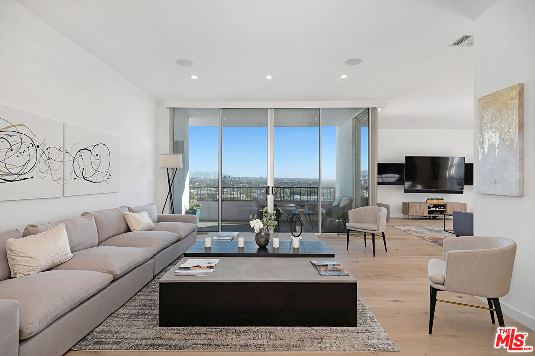 a living room with furniture a flat screen tv and a floor to ceiling window