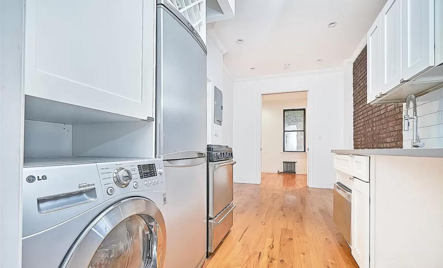 a view of a kitchen with stainless steel appliances wooden floor and living room view