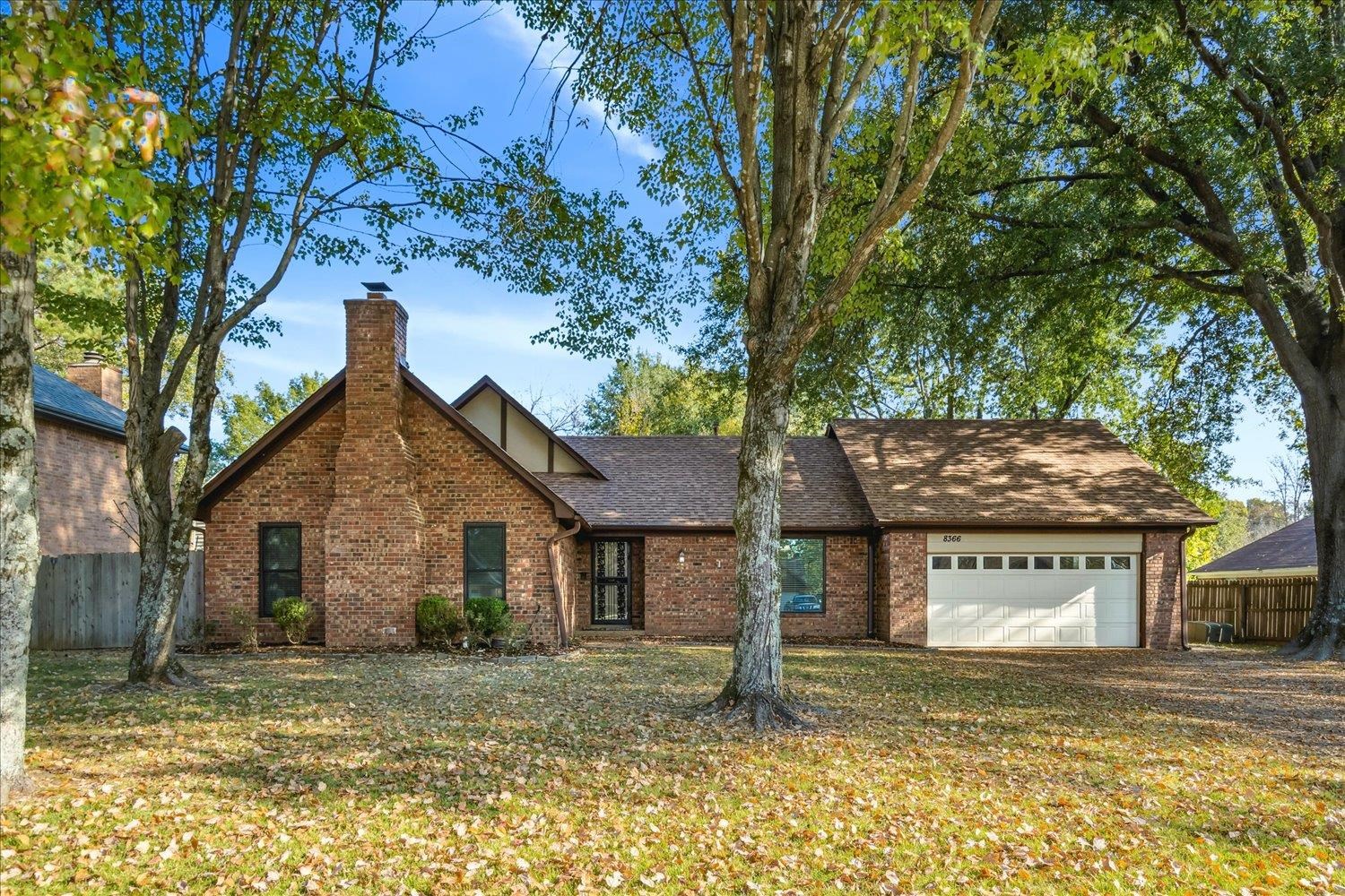 a view of a house with a yard and large tree